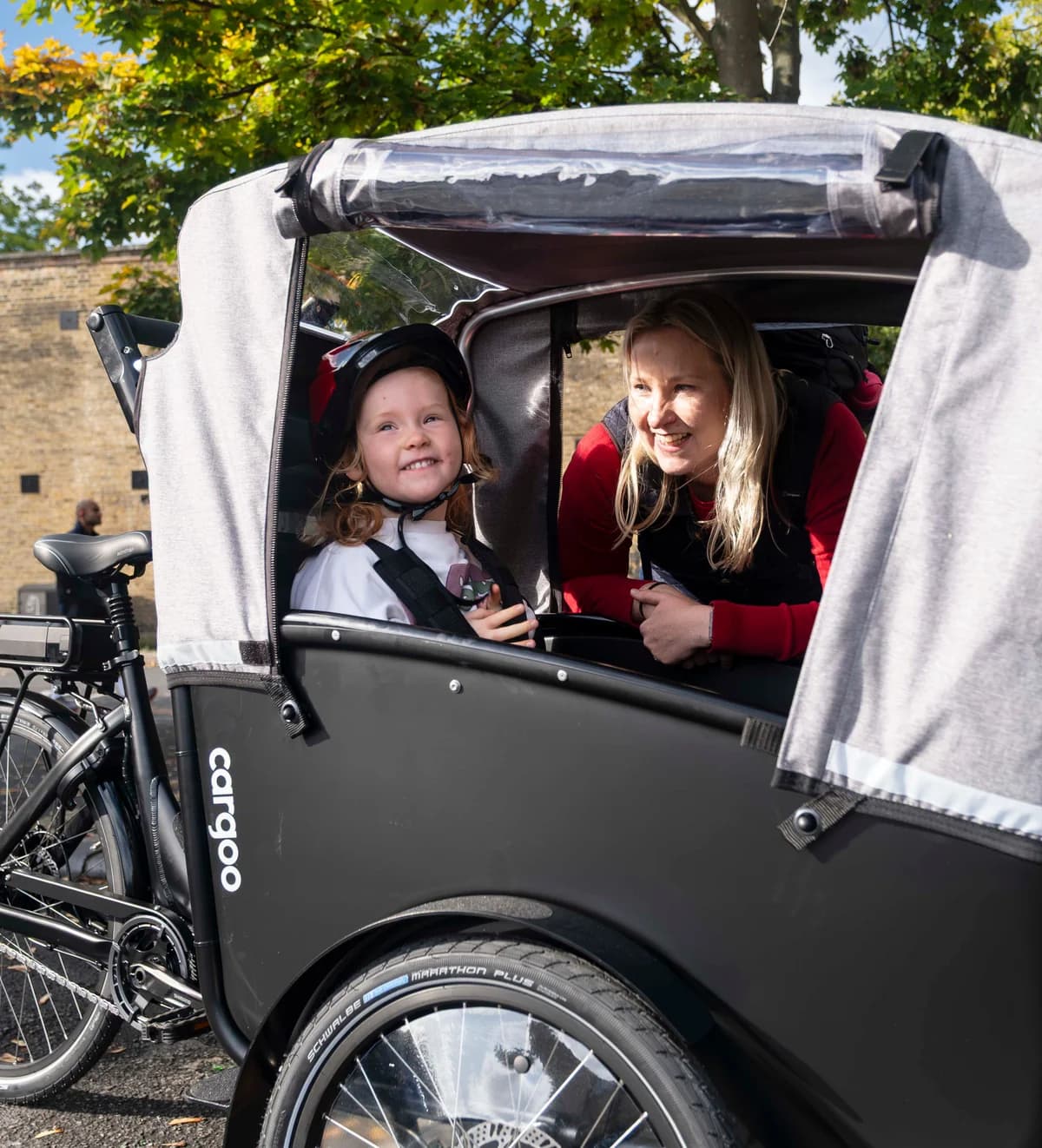 A parent and child riding in a cargo bike